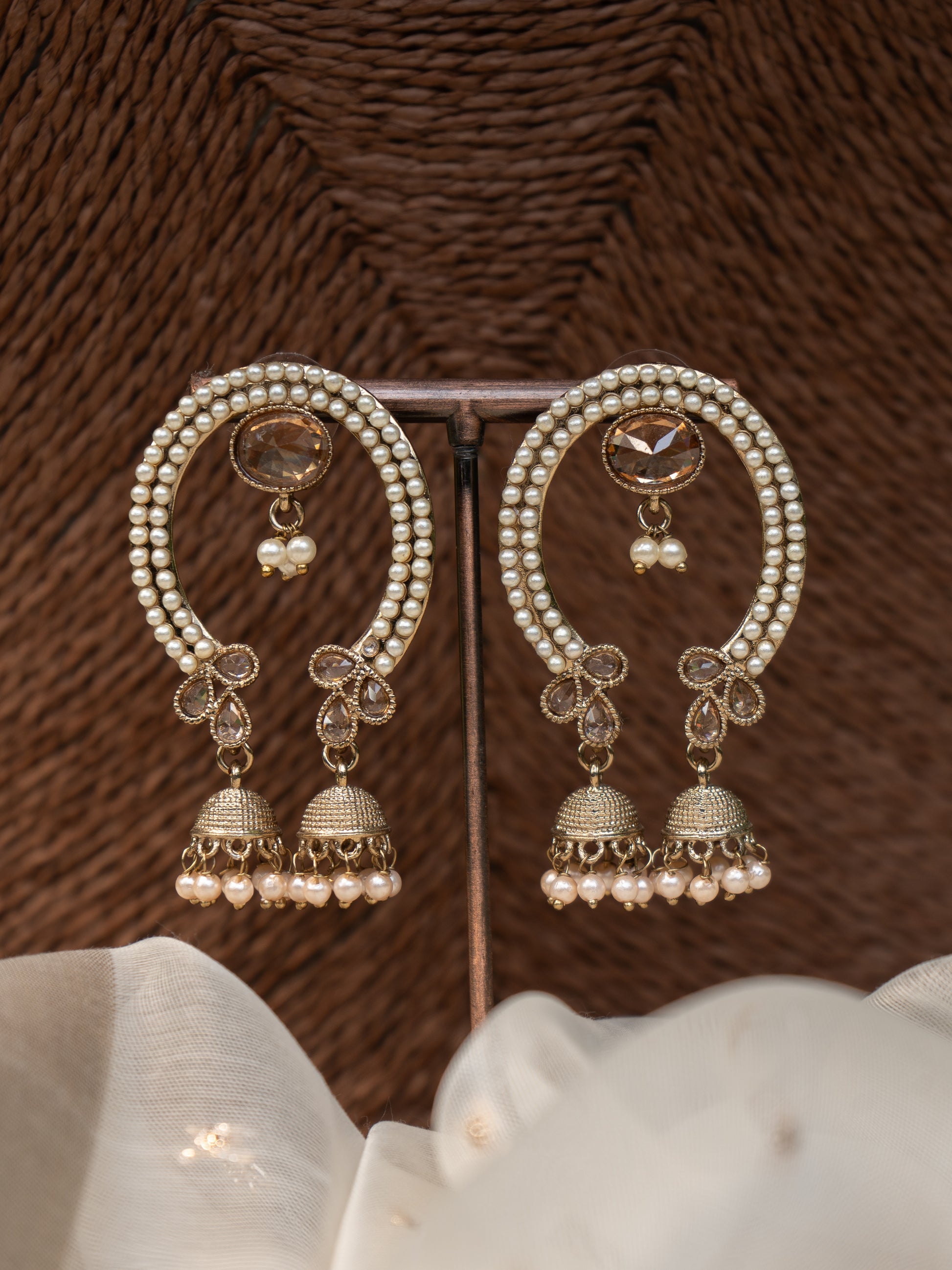 Arch-shaped festive earring with pearl detailing, central gemstone, and two jhumka