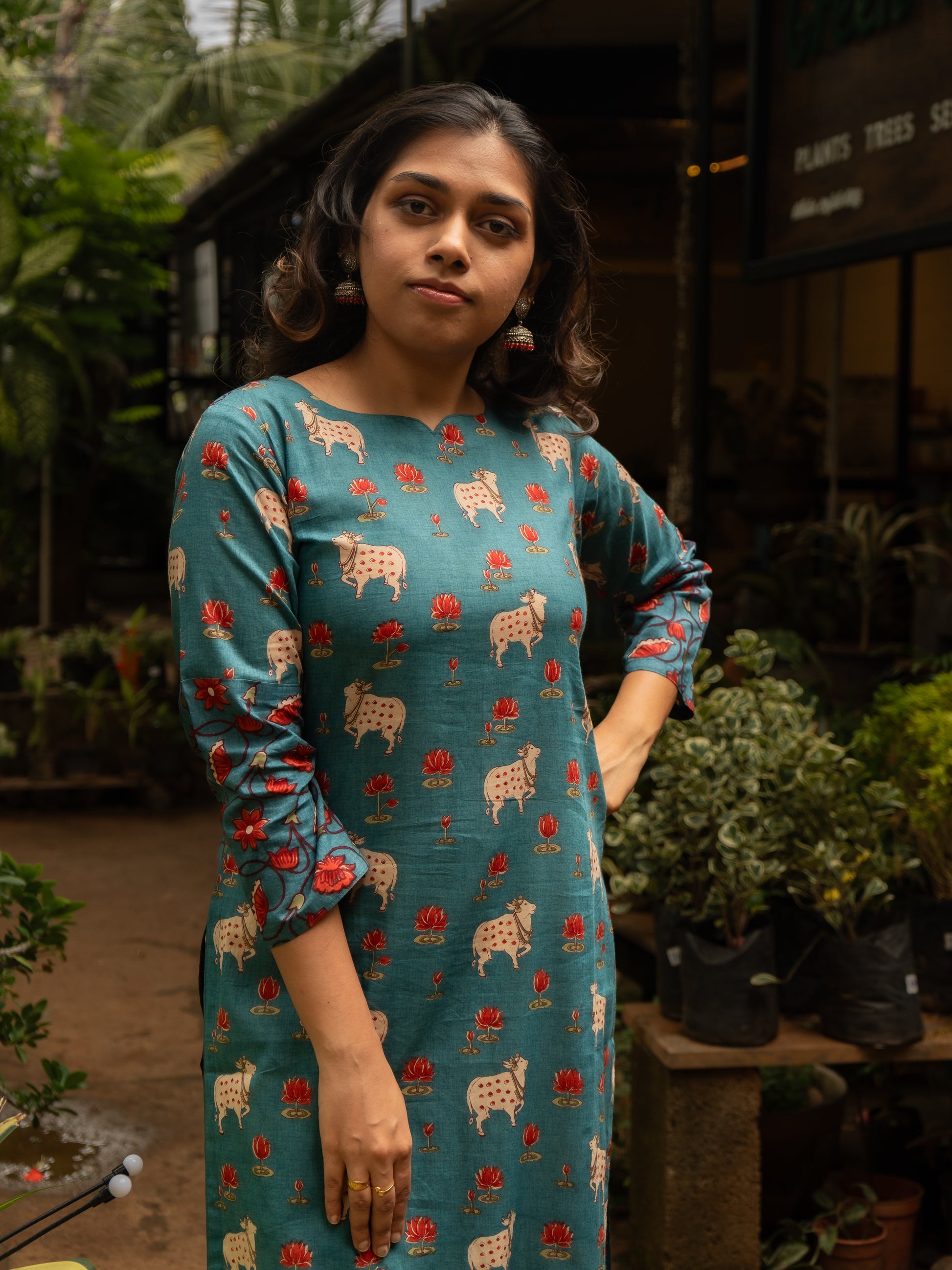 Mid-length view highlighting the unique curved bracket neckline and front Pichwai prints on blue cotton kurti, in-house design by Sakyaa.