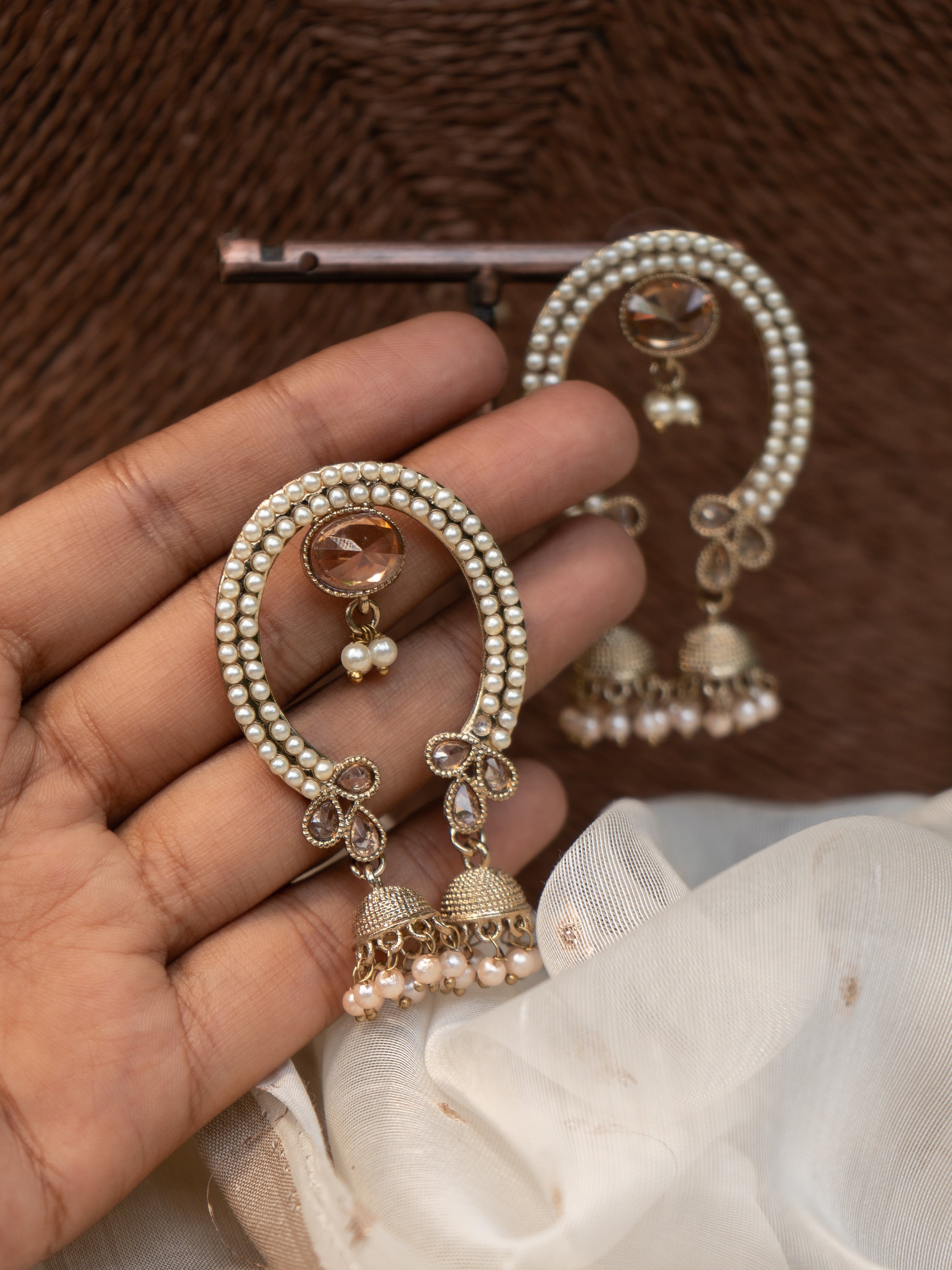 Close-up of pearl work, arch frame, and twin jhumkas in elegant ethnic earring