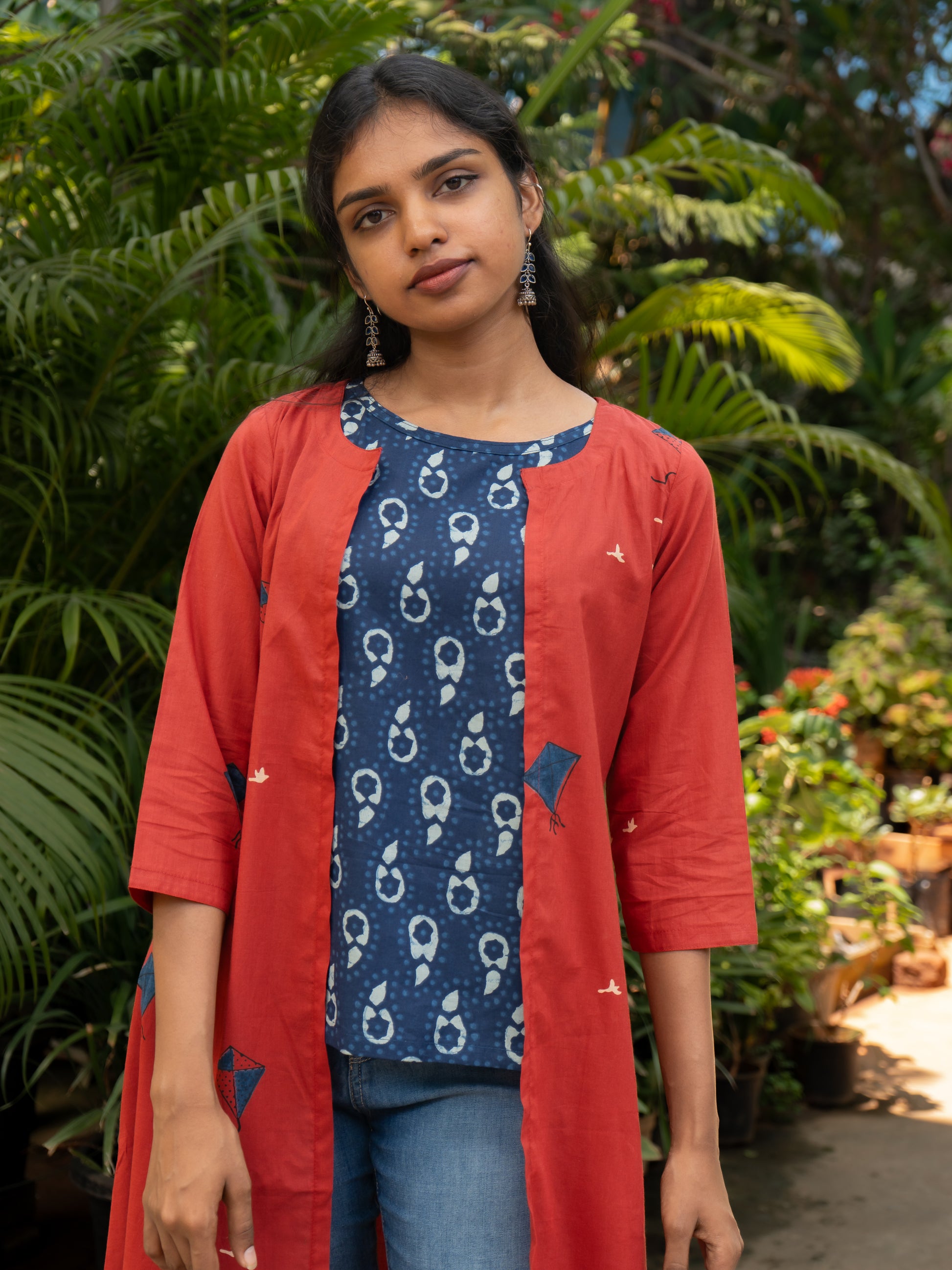 Close-up of red cotton cape jacket with blue kite print, A-line silhouette, round neck, and open front from Sakyaa.