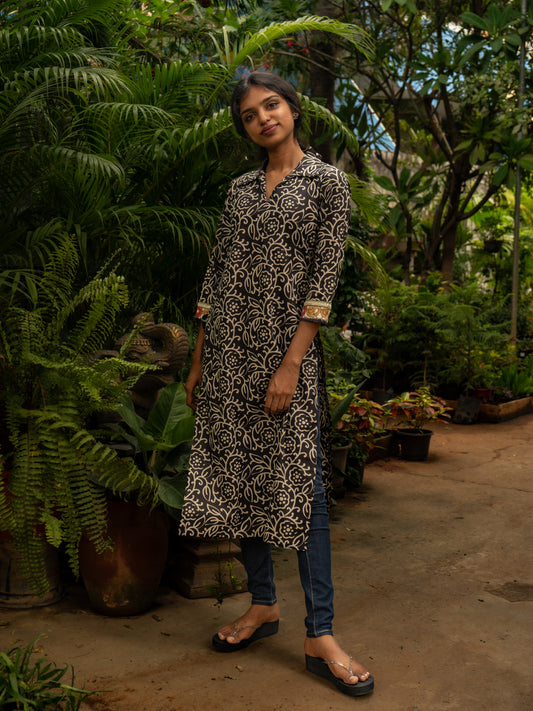 Front view of black and white cotton kurti featuring bold floral line-art prints, shirt collar, 3/4th sleeves, handcrafted in-house by Sakyaa tailors.
