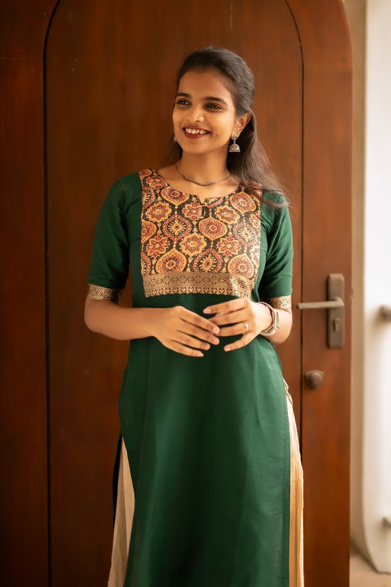 A bottle green cotton silk kurti with a printed silk yoke. The elbow length sleeves come decorated with a silk border as well.
